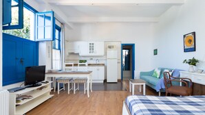 Ein kompakter Wohnraum mit Essbereich, Küchenzeile und einem Schlafzimmer mit Bett und Sitzecke.