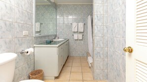 Un baño con azulejos de mármol, un lavabo, un inodoro y una zona de ducha.