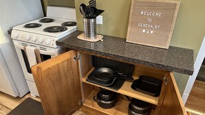 A kitchen with a built-in stove, a wooden cabinet with a black countertop, and a welcome sign.