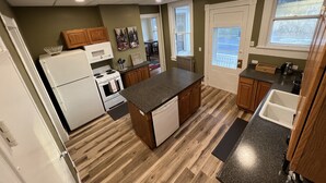 A compact kitchen with a central island, wooden cabinets, and a view to the outside.