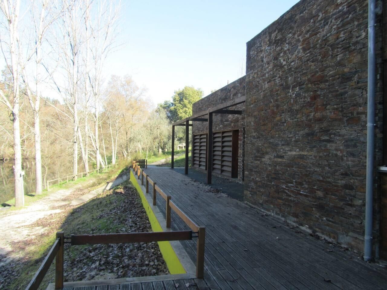 A pathway leading to a building with a stone facade and a wooden deck.