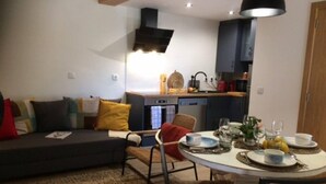 Un salon moderne avec un canapé, des fauteuils et une table à manger dressée pour le repas.