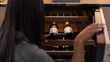 A person opening a wooden wine rack in a room with a book titled "TRAVEL" on the table.