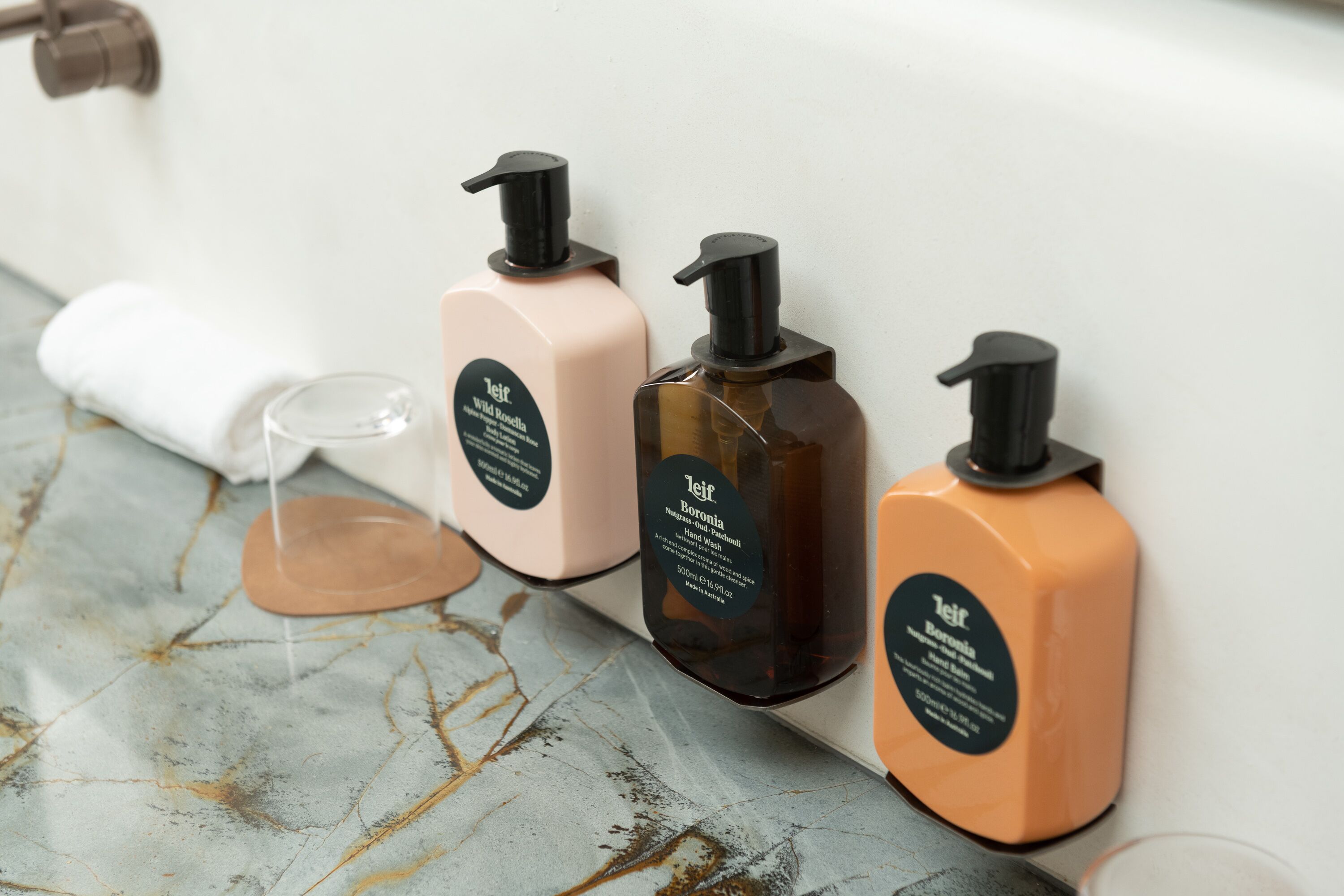 Three bottles of toiletries on a marble countertop.