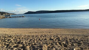 A beach with a rocky shoreline, calm water, and distant hills.