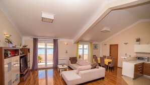 A spacious living area with a sofa, dining table, and kitchenette.