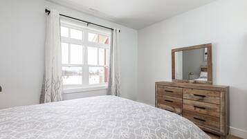 Een slaapkamer met een bed, een kaptafel met spiegel en een raam met gordijnen.