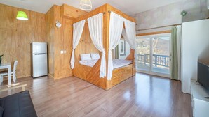 A bedroom with a four-poster bed, wooden walls, a large window, and a TV. - Ganghwa Herb Pension (Incheon)