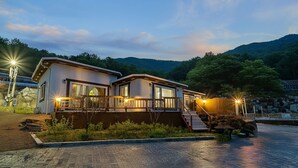 A two-story lodge with a balcony, a wooden deck, and a stone pathway leading to the entrance. - Ganghwa Herb Pension (Incheon)