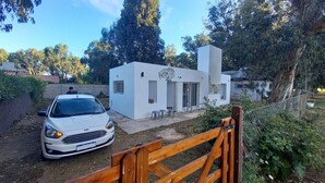 A white building with a fish mural, a car parked in front, and a wooden gate. - Cabin in Playa Dorada (Mar chiquita)