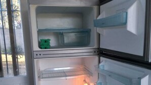 An open refrigerator with multiple shelves and drawers, a window on the left, and a door on the right. - Cabin in Playa Dorada (Mar chiquita)
