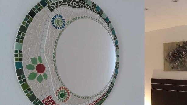 A circular mosaic wall art with a central white circle surrounded by green, red, and blue tiles. - Cabin in Playa Dorada (Mar chiquita)