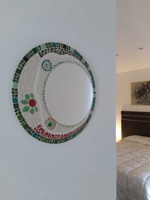A circular mosaic wall art with a central white circle surrounded by green, red, and blue tiles. - Cabin in Playa Dorada (Mar chiquita)