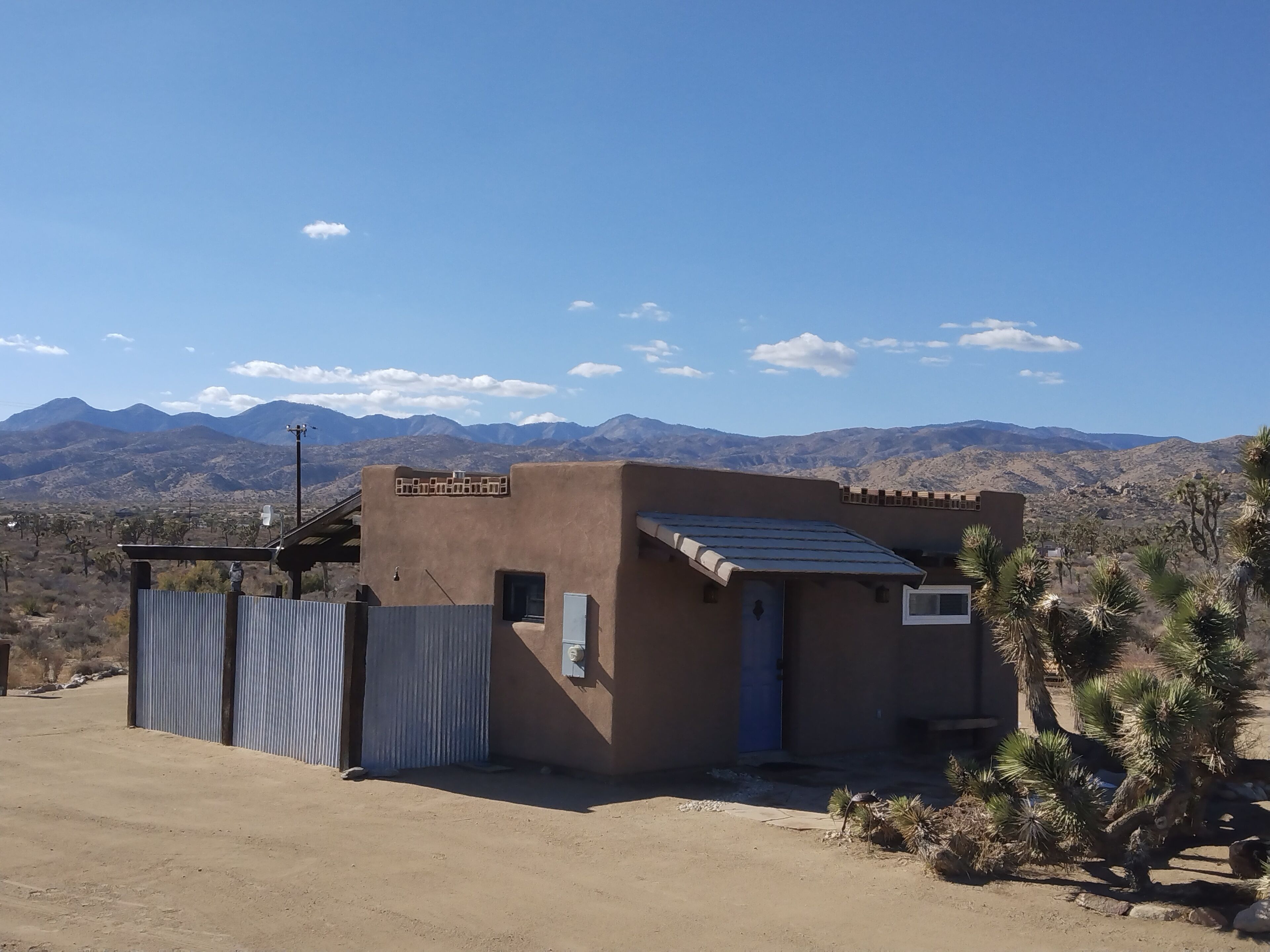 A small, single-story building with a flat roof and a corrugated metal fence.
