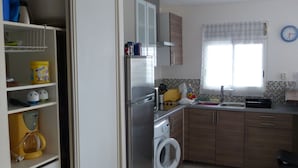 Una cocina compacta con lavadora, refrigerador y lavamanos.