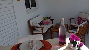 Un comedor con una mesa preparada para dos personas, una botella de agua y un florero con flores.