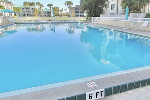 Relax by the pool surrounded by lounge chairs and umbrellas, with a clear view of the surrounding building and lush greenery.