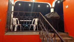 A staircase leading to a balcony with a view of the night sky, a railing, and a covered area with chairs.