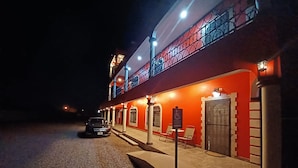 A two-story building with a red facade, a balcony with a metal railing, and a sign indicating wheelchair accessibility.