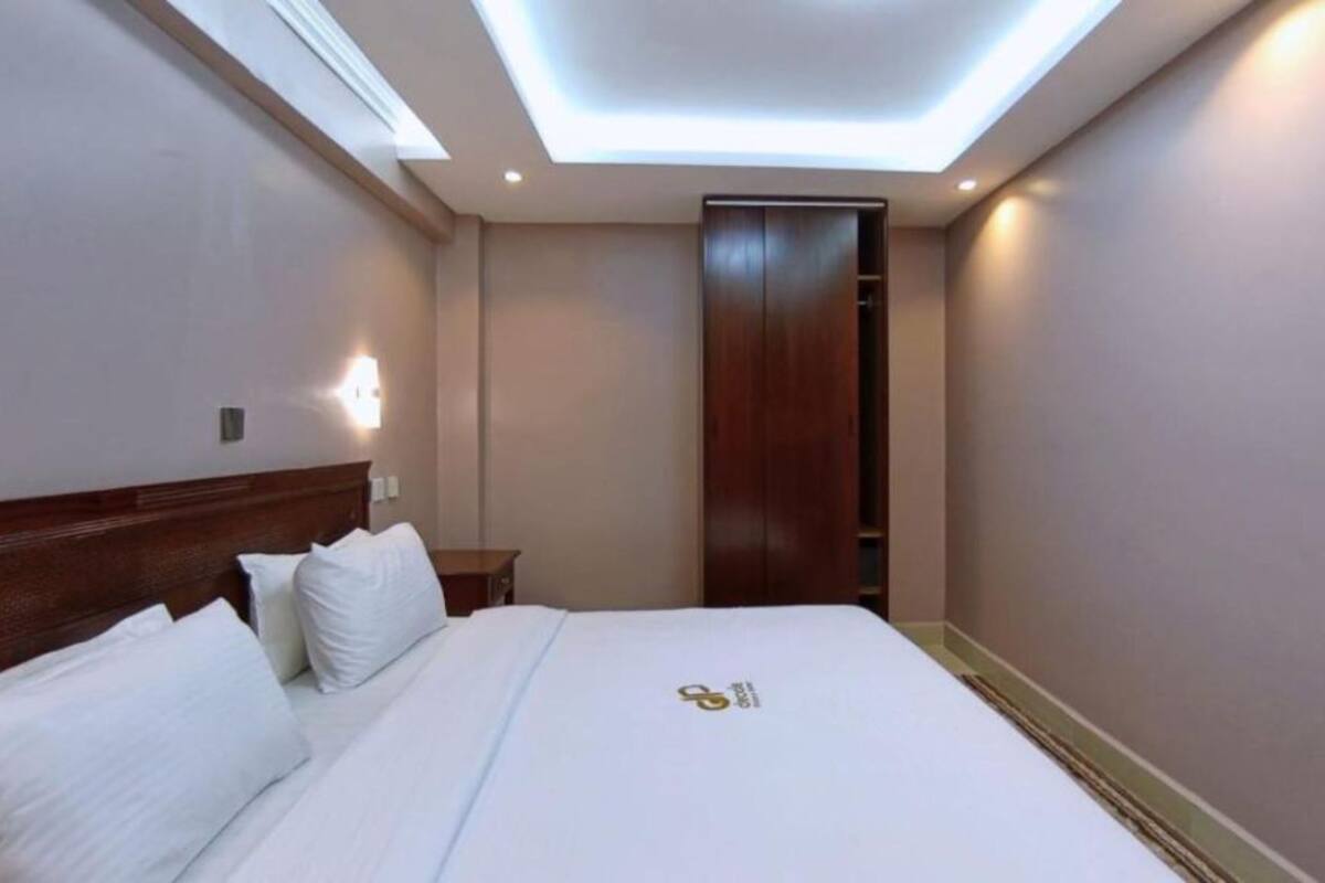 A hotel room with a bed, bedside table, and a wardrobe.