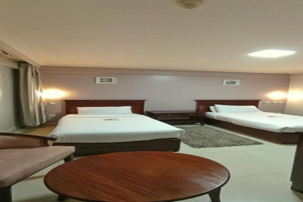 A hotel room with two single beds, a small round table, and a desk.