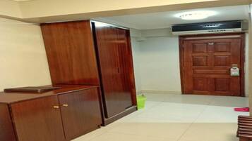 Ein Zimmer mit einem Holfischschrank, einem Schreibtisch, einem grünen Mülleimer und einer geschlossenen Holztür.