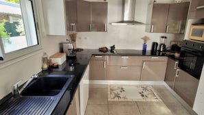 A modern kitchen with stainless steel appliances, a black sink, and a window providing a view of the outdoors. - Bleu Salé, magnificent waterfront villa (L'Étang-Salé)