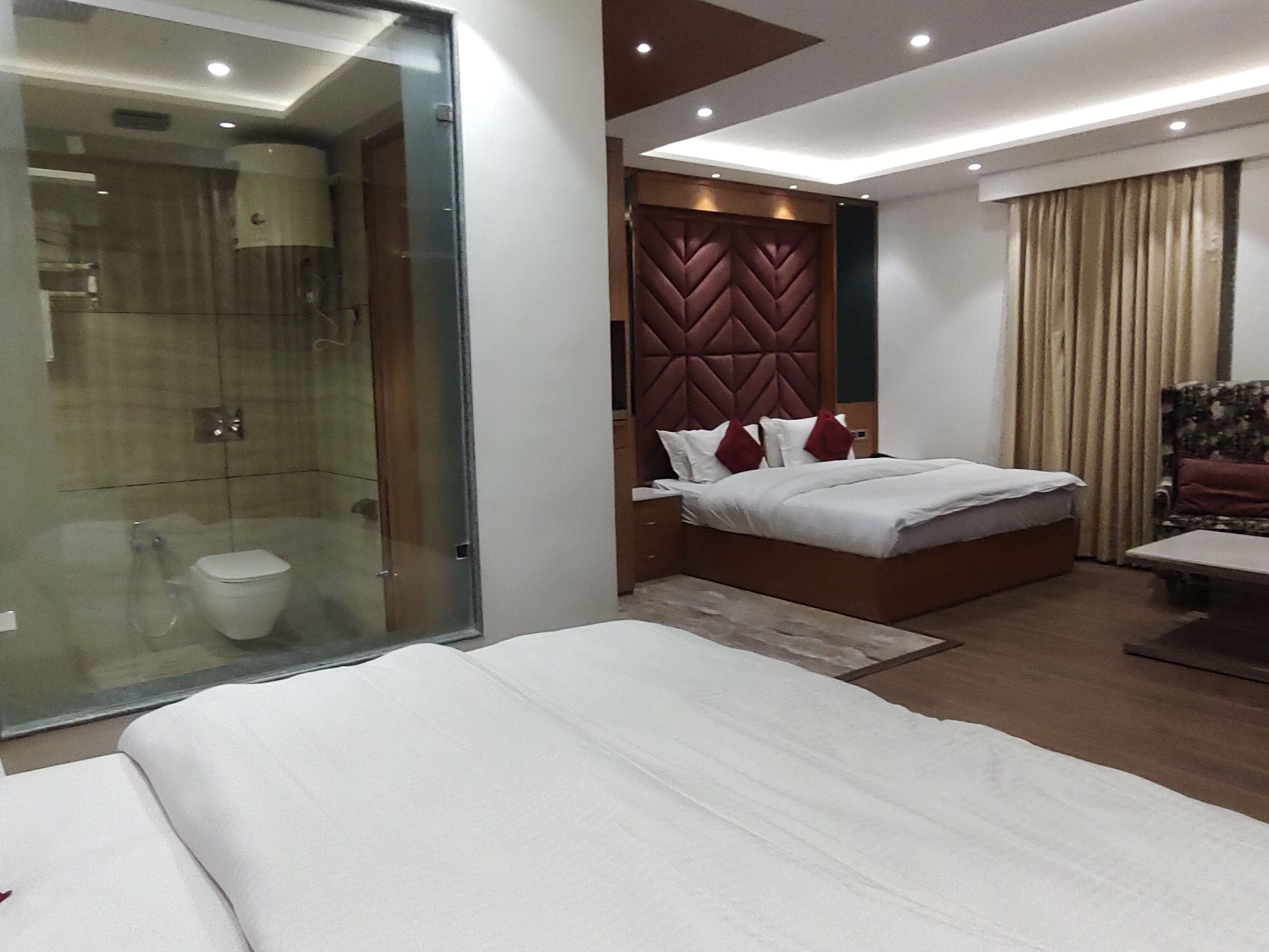 Quarto de hotel moderno com uma cama grande, banheiro separado e uma pequena área de estar.