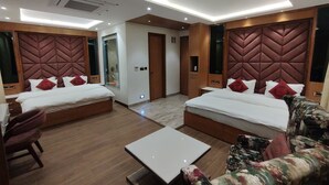 Une chambre d’hôtel moderne avec deux lits, un canapé, une table basse et un grand miroir.