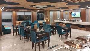Un restaurant avec des poutres en bois au plafond, un coin bar et un écran de télévision.