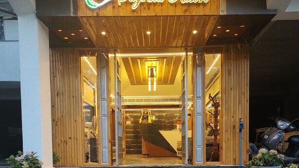 L’entrée d’un hôtel avec une façade en bois, une enseigne au néon et des marches menant à l’entrée.