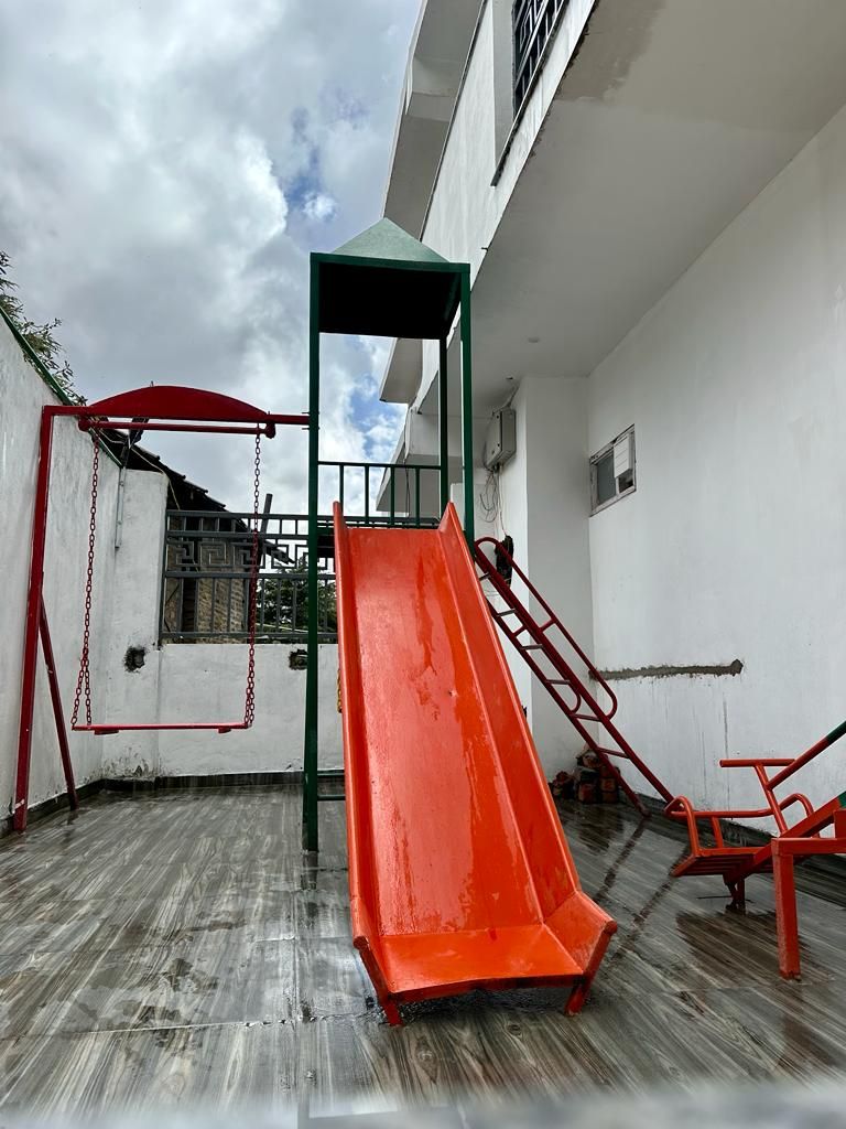 Un parque infantil con tobogán y columpios.