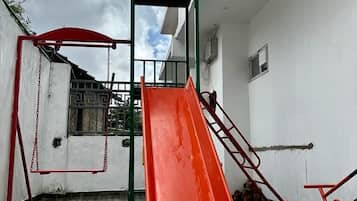 Un parque infantil con tobogán y columpios.