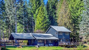 A two-story house with a metal roof, surrounded by a forest. - Waterfront Cabin at White Pass, Mt. Rainier (Packwood)