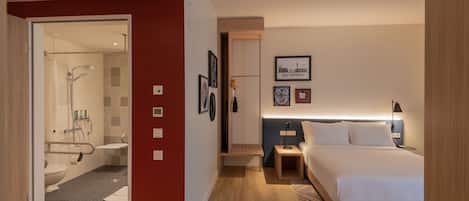 Una habitación de hotel moderna con ducha, inodoro, mesita de noche y una cama.