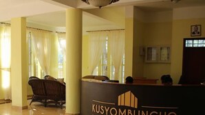 A reception area with a reception desk labeled "KUSYOMBUNGUO Hotels Ltd." and a circular decorative floor design. - Kusyombunguo Hotel Lukenya (Athi River)