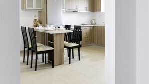 A modern kitchen with wooden cabinets, a dining area with chairs, and a white tiled floor. - Kolymbia Dreams Luxury Apartment 101 With Terrace Private Pool (Rhodes)