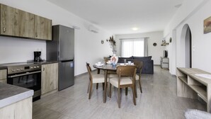 Eine moderne Küche mit Essbereich, ausgestattet mit einem Edelstahl-Kühlschrank, Backofen und einer Kaffeemaschine.