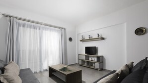 Una sala de estar moderna con sofá, mesa de centro, mueble para televisión y cortinas.