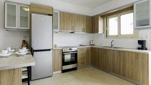 Una cocina moderna con armarios de madera, horno empotrado, refrigerador y ventana.