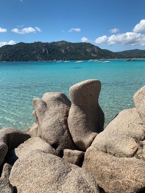 A rocky shoreline with clear turquoise water and distant mountains. - Garden Apartment (Lecci)