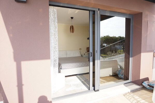 A bedroom with a bed, a nightstand, and a hanging light fixture. - Beautiful Villa With Private Pool by Beahost (Rosolina)