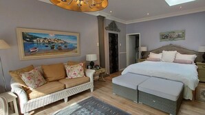 A bedroom with a large bed, a sofa, a nightstand, a dresser, and a painting on the wall. - Platinum Suite With Private Terrace! For 2 Guests - Roosboom Luxury Apartment (Cape Town)