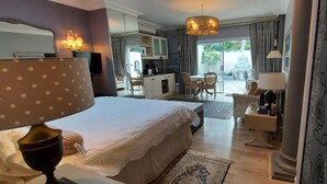 A hotel room with a bed, a desk, a chair, a dining table, and a view of the garden. - Platinum Suite With Private Terrace! For 2 Guests - Roosboom Luxury Apartment (Cape Town)
