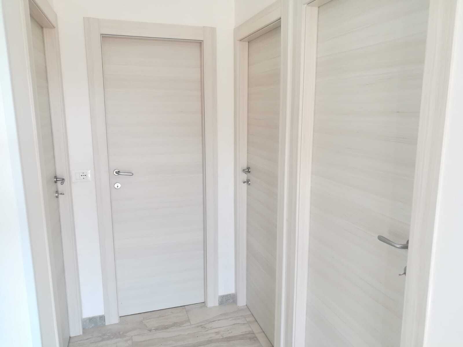 Passadís amb una porta tancada, un interruptor de llum i un tirador de porta.