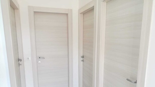 A hallway with a closed door, a light switch, and a door handle.