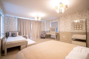 Ein Hotelzimmer mit zwei Betten, einem Schreibtisch, einem Stuhl, einem Spiegel und einer Chandelier.
