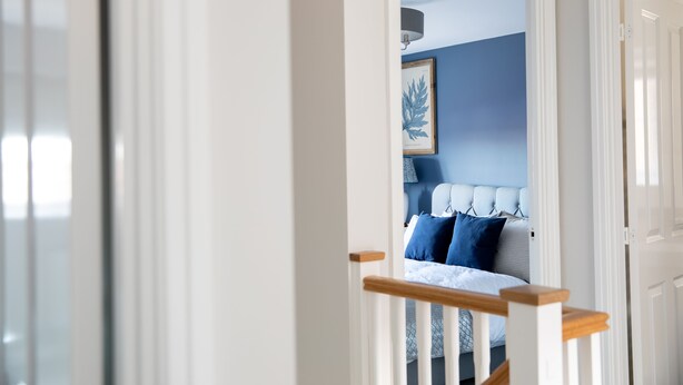 A bedroom with a bed, a framed artwork on the wall, and a blue accent wall.