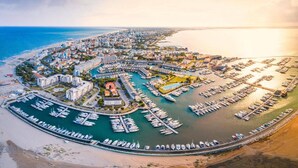 An aerial view of a coastal city with a marina filled with boats, surrounded by residential buildings and a beach. - Very Nice Flat With Swimming Pool (Lignano Sabbiadoro)