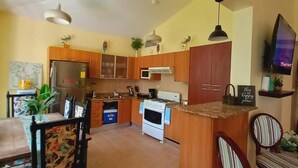 A kitchen with wooden cabinets, a refrigerator, microwave, stove, and a dining area with chairs and a table. - "las Brisas, Juan Dolio, 3 Bedrooms, 3 Pools, Jacuzzi, Beach, Golf,polo" (Guayacanes)